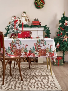 Detalle de mantel navideño con diseño de pueblo festivo y bastones de caramelo en mesa