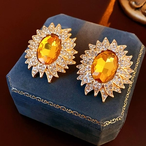 Close-up of vintage sunflower earrings with yellow gems on blue velvet jewelry box