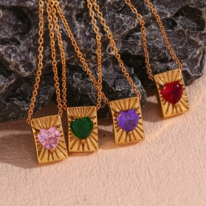 Close-up of heart-shaped zircon pendants in four colors with gold sunburst engraved plates