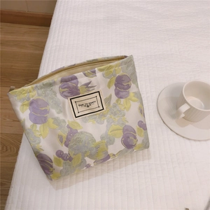 Detailed fabric makeup bag with tulip prints and Time to Party label on a bed