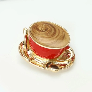 Detailed macro view of a red enamel coffee cup brooch with golden saucer and spoon