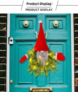 Close-up of lighted Christmas gnome wreath with LED lights and red hat on a blue door