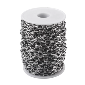 Macro shot of silver stainless steel rectangular link chain wound on a white spool