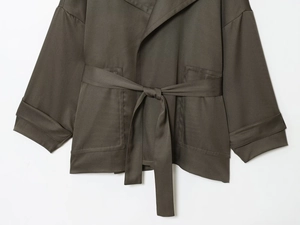 Detail der dunkeloliven Gürteljacke mit Taillenbindung und großen Seitentaschen