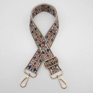 Detailed view of jacquard embroidered bag strap with golden metal hooks and adjustable buckle
