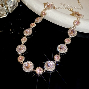 Detail der rosa Kristallkette mit Goldbasis und funkelnden Diamanten auf schwarzem Grund