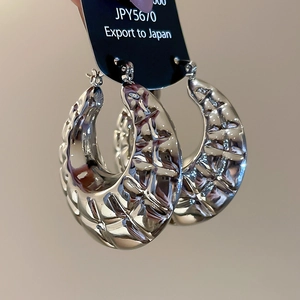 Macro shot of silver C-shaped chunky earrings featuring textured geometric patterns
