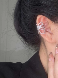 Close-up of a silver butterfly ear cuff with sparkling cubic zirconia on a model's ear
