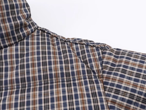 Detailed close-up of the plaid pattern collar and shoulder stitching on a cotton jacket