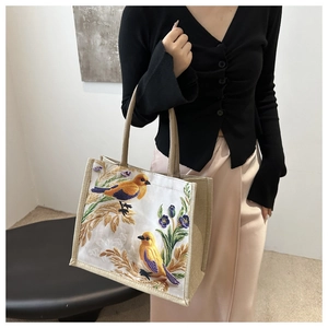 Linen tote bag with bird embroidery carried by a model in a modern fashion outfit