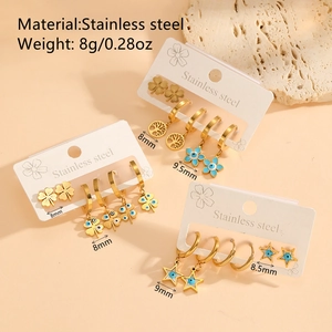 Golden stainless steel earring sets with star and clover charms on a pink background