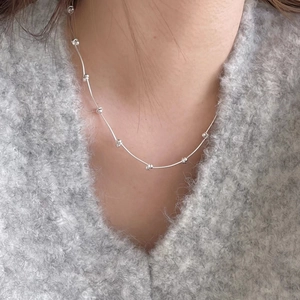Detail showing simple 925 silver beaded necklace worn on a cozy grey sweater