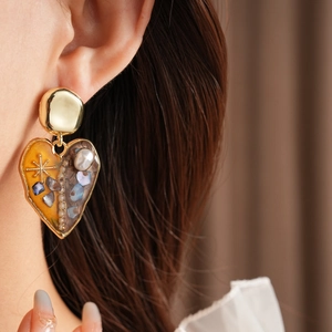 Detailed view of vintage heart earrings featuring amber resin and mixed pearl embellishments