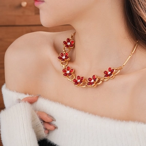 Detail of vintage gold necklace featuring red glass flowers with small white diamonds