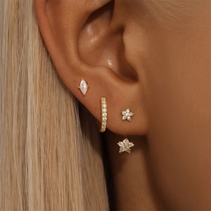 Close-up of gold S925 silver evil eye and teardrop earring set on a model's ear