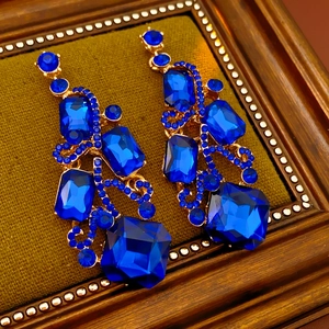 Detail of vintage gold-tone earrings with multifaceted blue gemstones and rhinestones