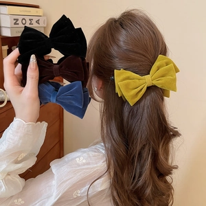 Close-up of velvet bow hair clips in black, yellow, blue, and dark brown colors