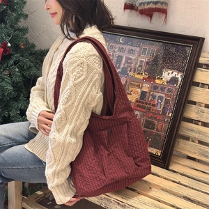Detail view of red plaid canvas tote bag with snap pocket on a winter scene model