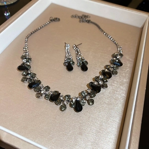 Detailed view of silver jewelry set with black gemstones and crystals in a gift box