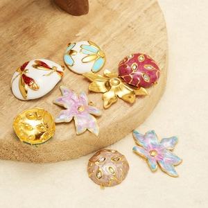 Detailed view of enamel flower and insect pendants with gold plating and rhinestones