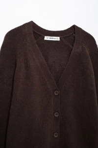 Detail der braunen Strickjacke mit V-Ausschnitt, gebürsteter Textur und dunklen Knöpfen