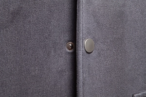 Gros plan sur les boutons-pression en métal mat de la veste en daim gris et coutures