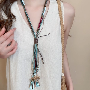 Detail view of multi-layer bohemian necklace with blue tassels and golden heart pendant