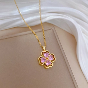 Detail of clover necklace with pink heart-shaped gems on white silk and golden chain
