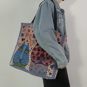 Detail of printed canvas tote bag featuring cute cat and heart patterns on woven texture
