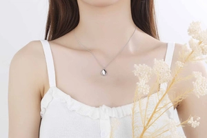 Macro detail of a silver oval pendant necklace showing smooth mirror-like finish on skin