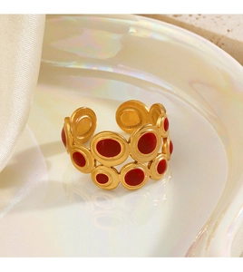 Detail of a gold geometric ring with red enamel inlays on a pearl-like white tray