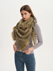 Detail of plaid scarf with tassels showing brown and yellow knit texture on a model