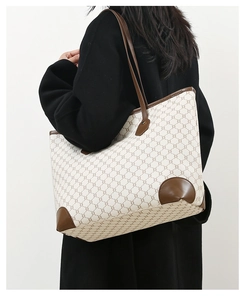Model wearing a large capacity beige tote bag with brown geometric pattern and leather trim