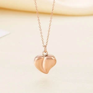 Macro close-up of a polished rose gold heart pendant on a minimalist chain necklace