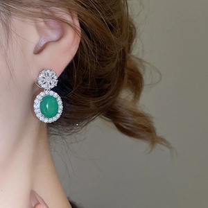 Gros plan de boucles d'oreilles en argent avec pierres vertes ovales et zircons brillants
