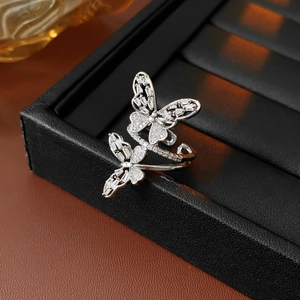 Macro detail of silver butterfly ring with white zircon stones on a black leather box
