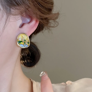 Gros plan de boucles d'oreilles vintage en émail floral portées par un modèle