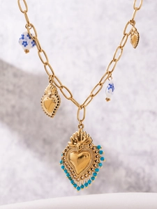 Gros plan détaillé du collier doré avec des perles en céramique et pendentifs en cœur