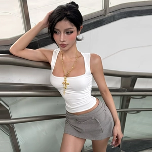 Detail view of white square-neck tank top with layered gold cross necklaces on a model