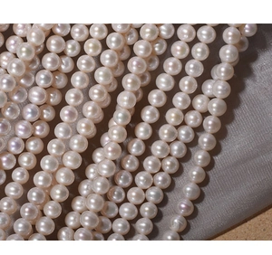 Macro detail of high-luster 7mm pink-white freshwater pearls arranged on silk fabric