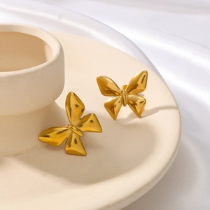 Minimalist 18K gold plated titanium steel bow earrings on a ceramic display tray