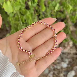 18K gold plated bracelet with red round zircons held by hand against natural background