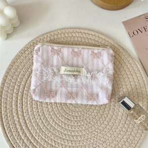 Detailed close-up of a lace floral coin purse with 3D pink bows and stripe texture