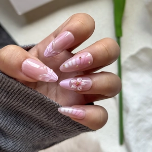 Detail of almond press-on nails featuring 3D gradient flowers and metallic bead accents