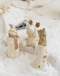 Detail of glowing white ceramic Christmas figurines with star cutouts and golden glitter