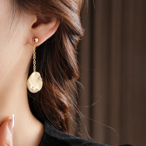 Détail de boucles d'oreilles asymétriques plaquées or 18k avec chaîne et cristaux