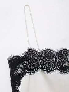 Detail of white satin camisole top featuring delicate black lace trim at the neckline
