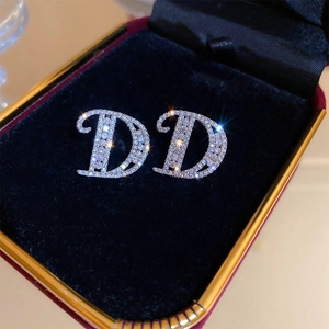 Macro detail of silver D-shape earrings with zircon pavé in a velvet jewelry box