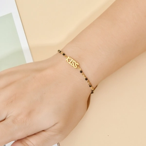 Golden stainless steel KISS bracelet with black beads on a female wrist accessory