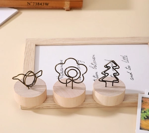 Détail de trois porte-cartes en bois avec clips en métal en forme d'oiseau fleur et sapin